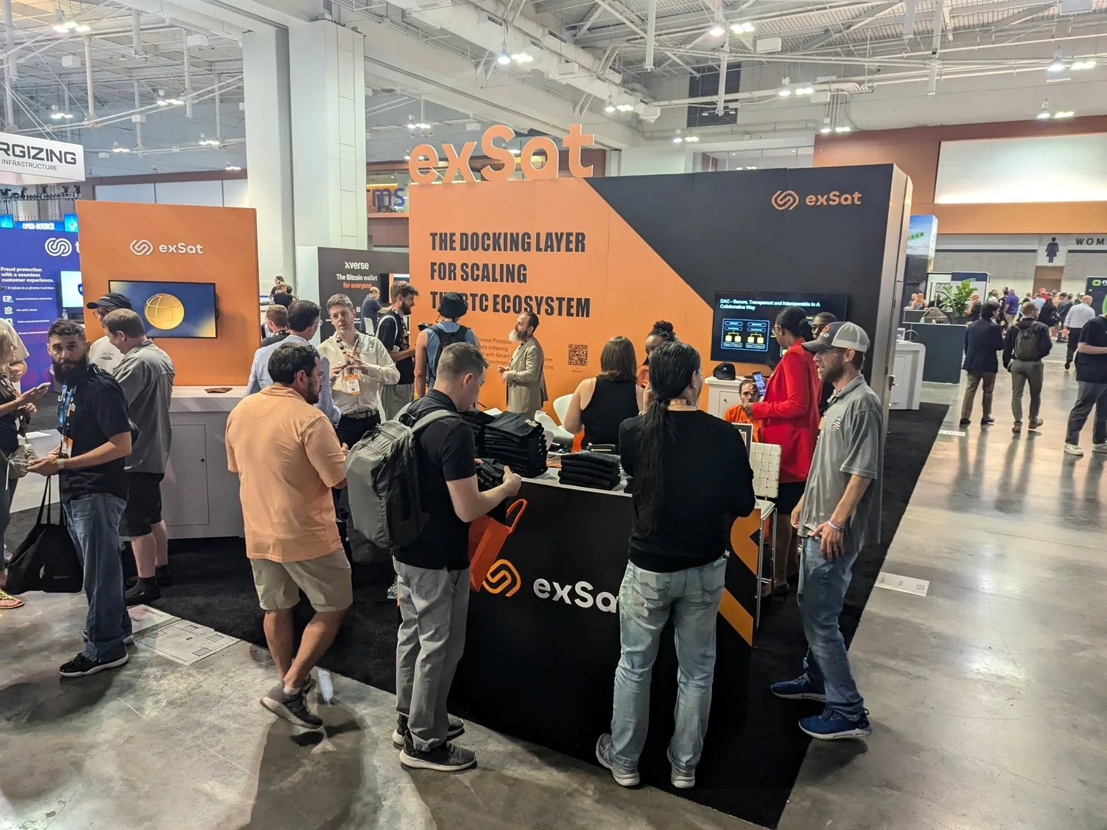 exSat booth at a Bitcoin conference, busy with visitors